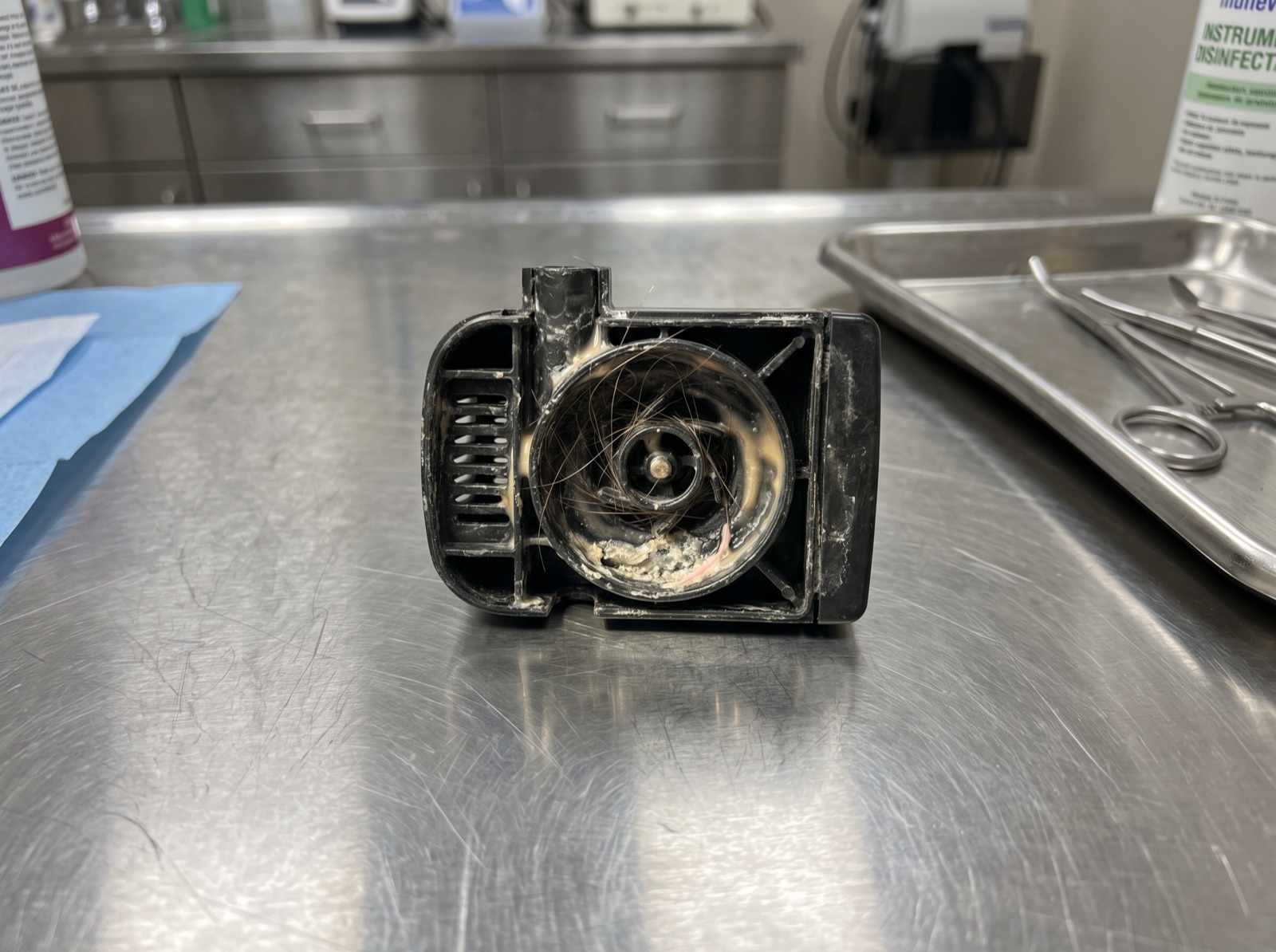 Macro shot: inside of a competitor pump shell at 48 hours. Hair wrapped around the pump motor, slime on the inside walls, scale at the base.